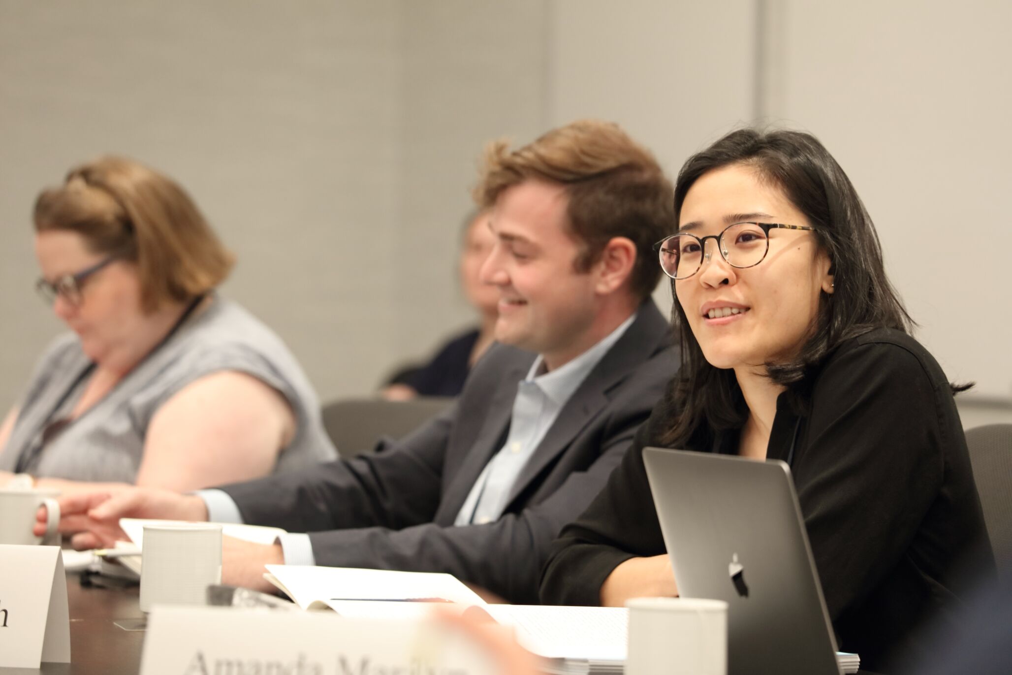 A woman discusses with her colleagues seated at a table.