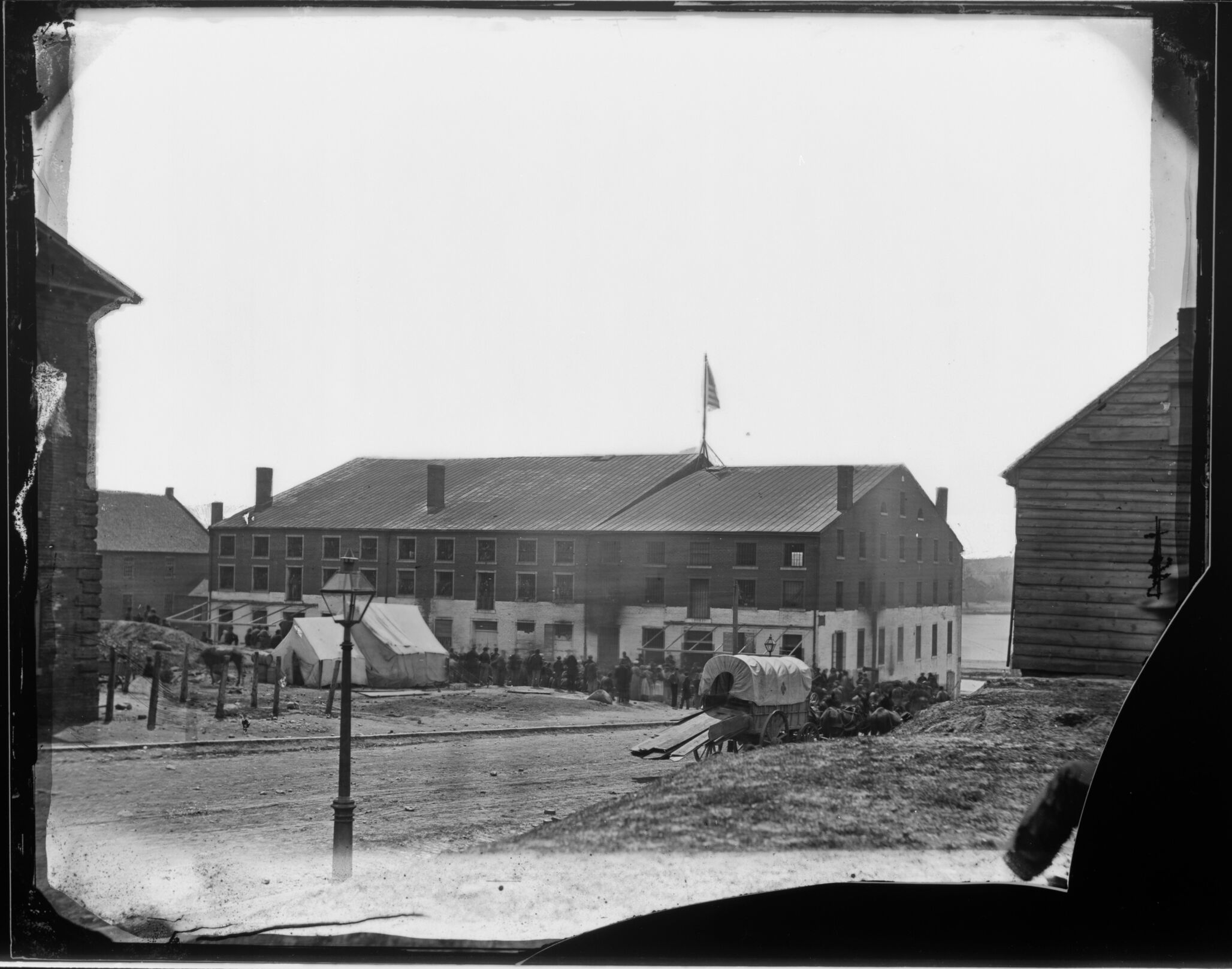 A historic photo of prisoners lined up outside of buildings at Libby Prison.